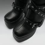 Black platform boots with multiple decorative straps, silver-tone grommets, and buckles, shown in a close-up studio shot.