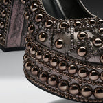 Close-up of a metallic studded shoe featuring rows of large rose gold dome studs and smaller dark metallic studs on a textured black and silver upper.