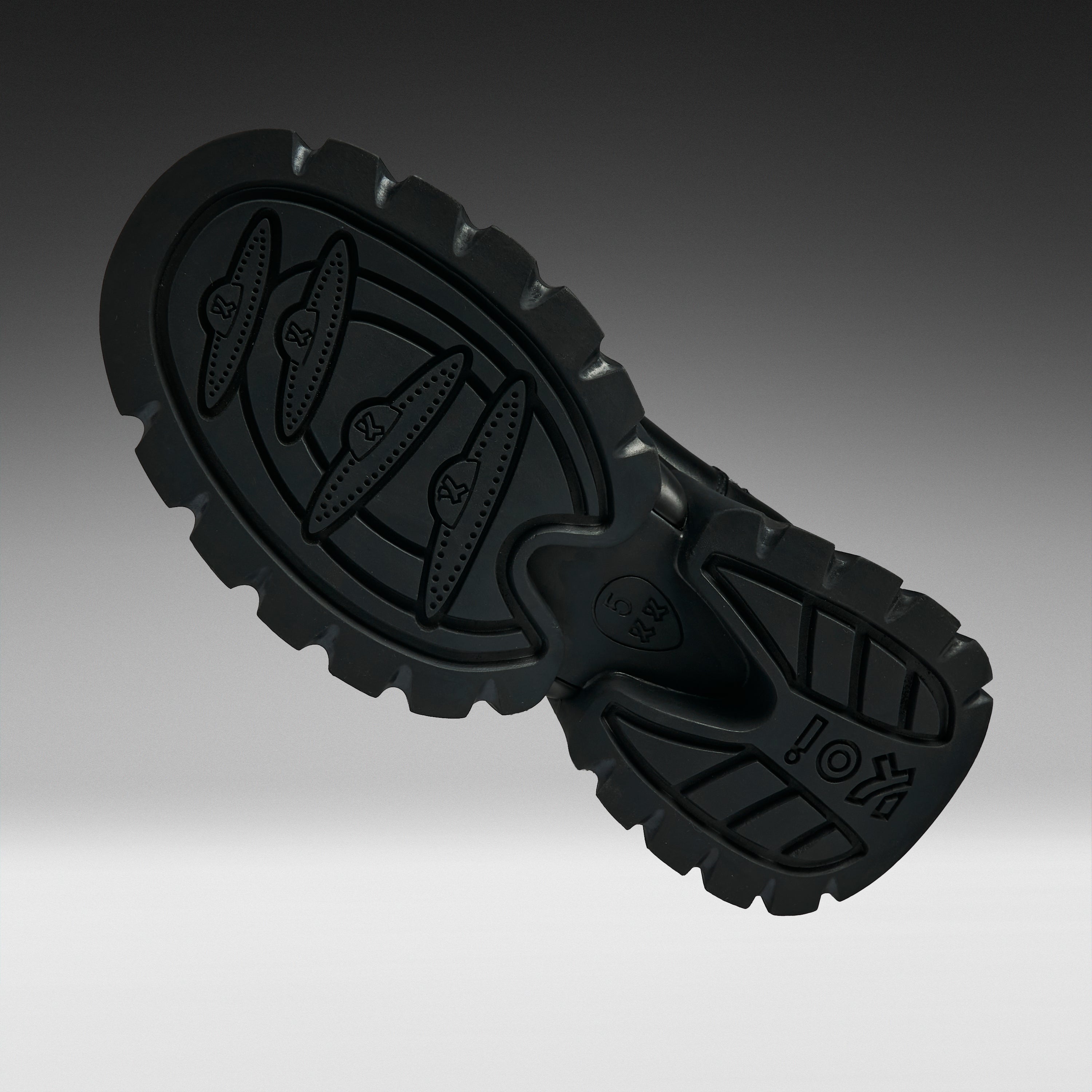 A close-up studio shot of a black rubber shoe sole, showing the tread pattern and embossed branding, set against a dark gray gradient background.