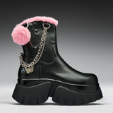 A black leather ankle boot with a chunky lug sole, decorated with a fluffy pink faux-fur trim, a pink pom-pom, and a silver chain with a butterfly charm.