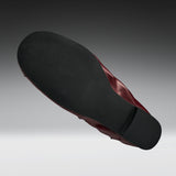 A single shoe shown from a high-angle back view, displaying a black textured outsole and a dark burgundy-red inner lining against a gray gradient background.