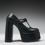 A single black leather platform Mary Jane shoe with a chunky block heel and double buckle straps, shown from a side profile on a dark gray to light gray gradient background.