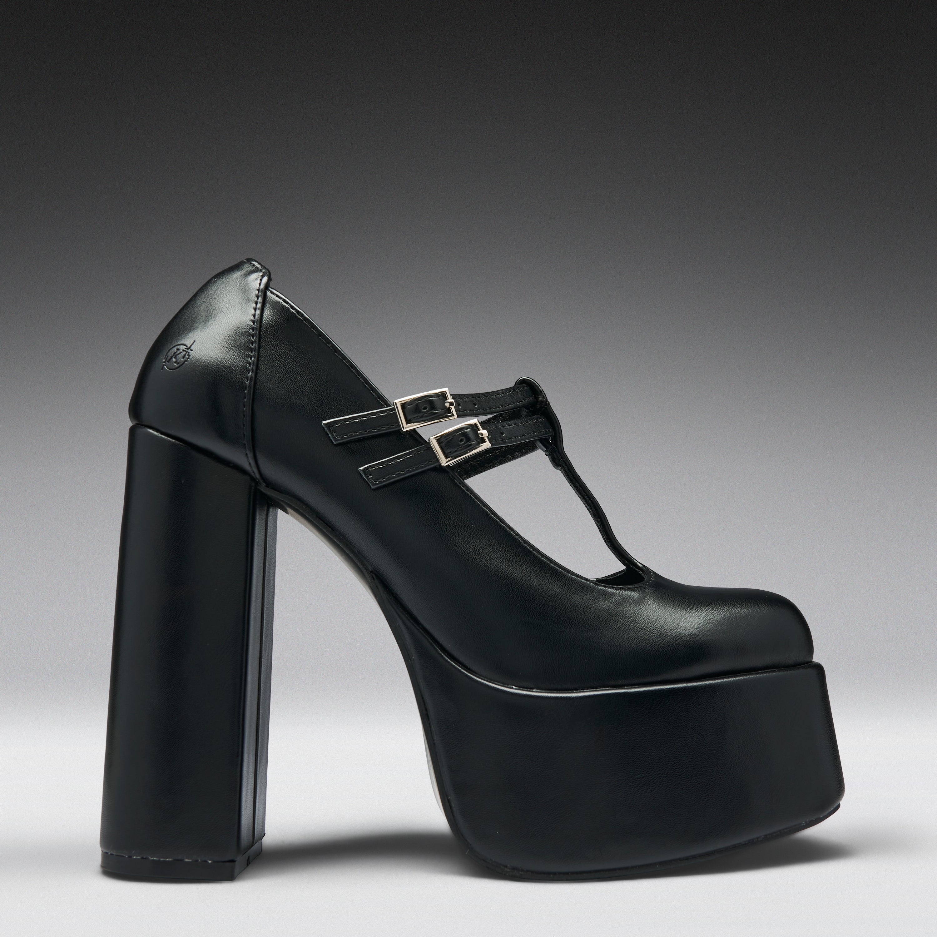 A single black leather platform Mary Jane shoe with a chunky block heel and double buckle straps, shown from a side profile on a dark gray to light gray gradient background.