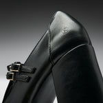 Close-up of a black leather boot with double buckle straps and a small embossed logo on the heel, photographed against a dark gray gradient background.