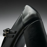 Close-up of a black leather boot with double buckle straps and a small embossed logo on the heel, photographed against a dark gray gradient background.