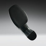 A close-up studio shot of the underside of a black athletic shoe, showing the textured outsole, heel, and a small section of the metallic outsole edge against a gray gradient background.