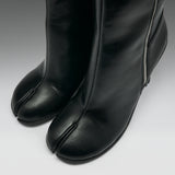 Close-up of a pair of black leather tab-cloth boots with a side zipper, shown on a neutral gray background.