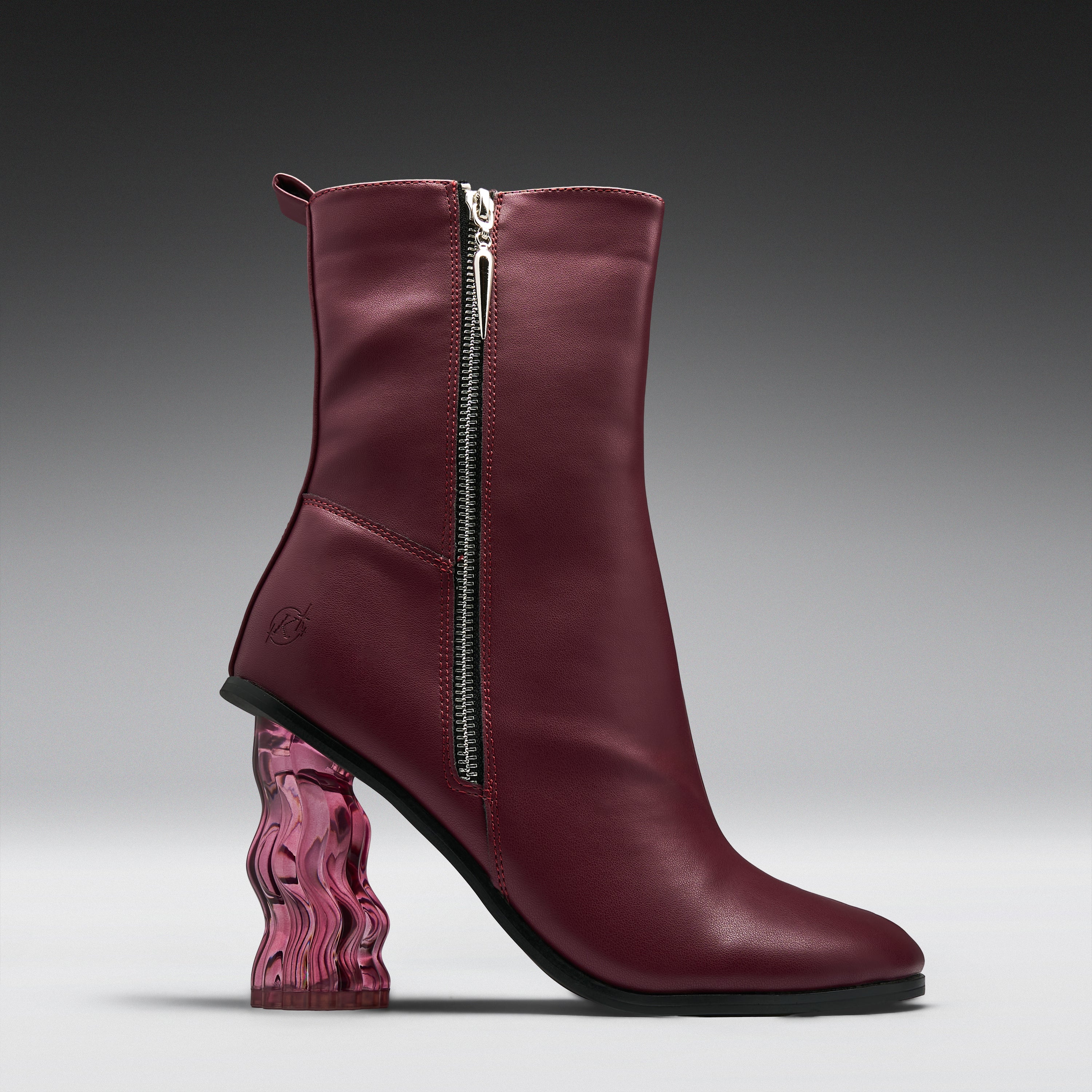 A single women's ankle boot in burgundy leather with a silver side zipper, a chunky wavy transparent pink block heel, and a black outsole, shown on a dark-to-light gray gradient studio background.