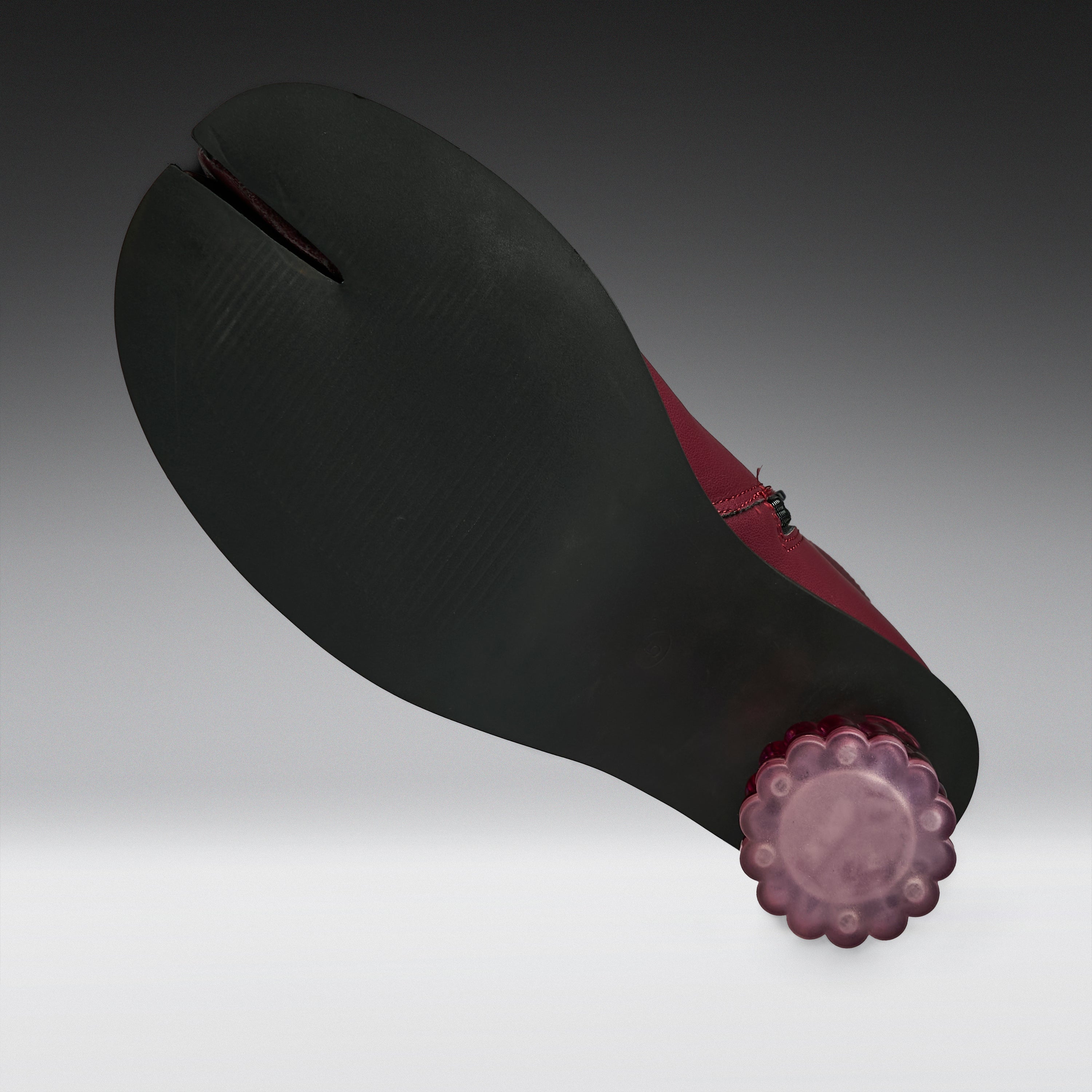 A traditional Japanese tabi-style foot strap shoe shown from the sole side, featuring a wide matte black foot strap with a central seam, a deep burgundy red inner lining, and a translucent purple flower-shaped end cap.