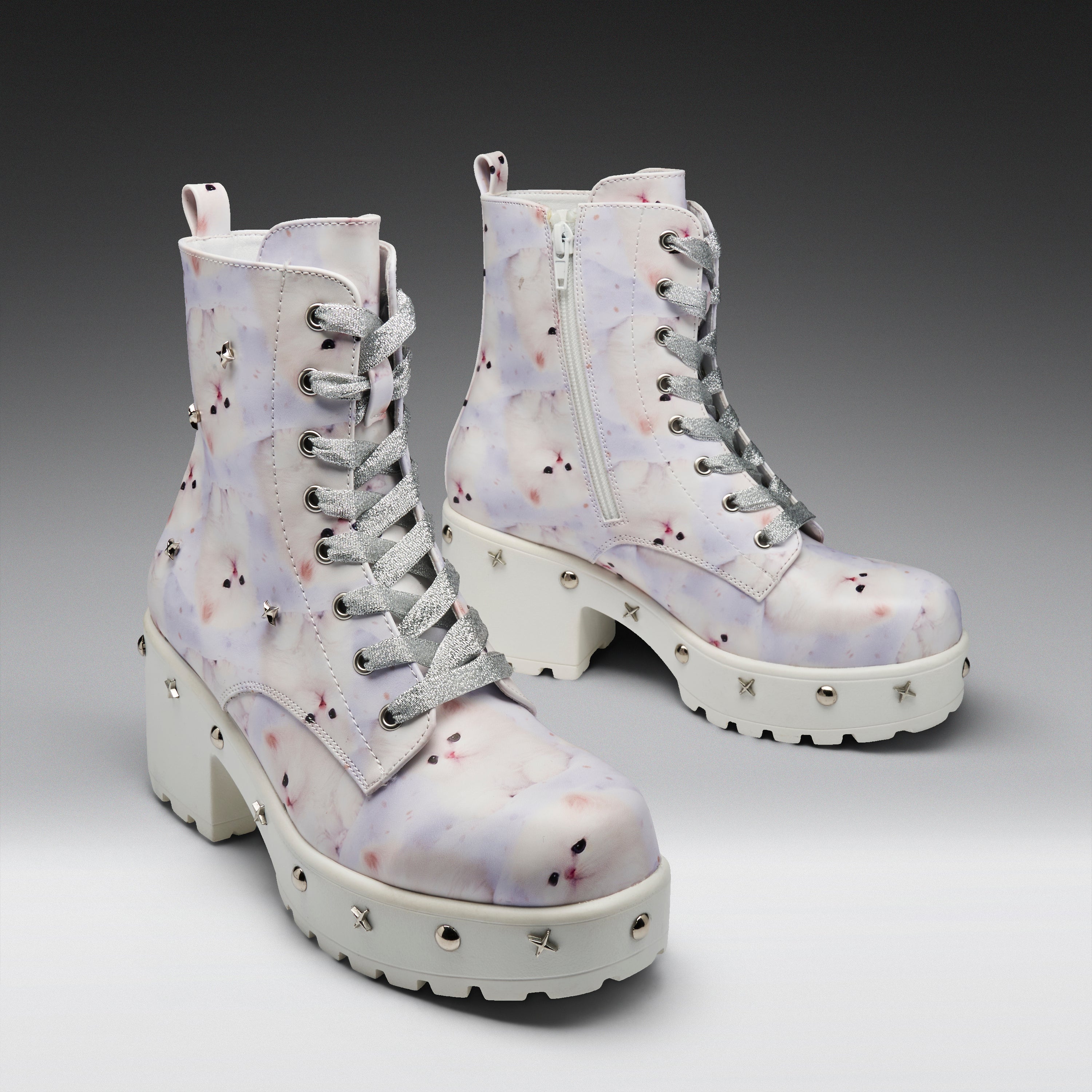 A pair of chunky lace-up ankle boots with a white base and a pastel purple, pink, and blue watercolor-style floral pattern. The boots feature silver metal studs on the thick white lug soles, gray laces, and a side zipper.