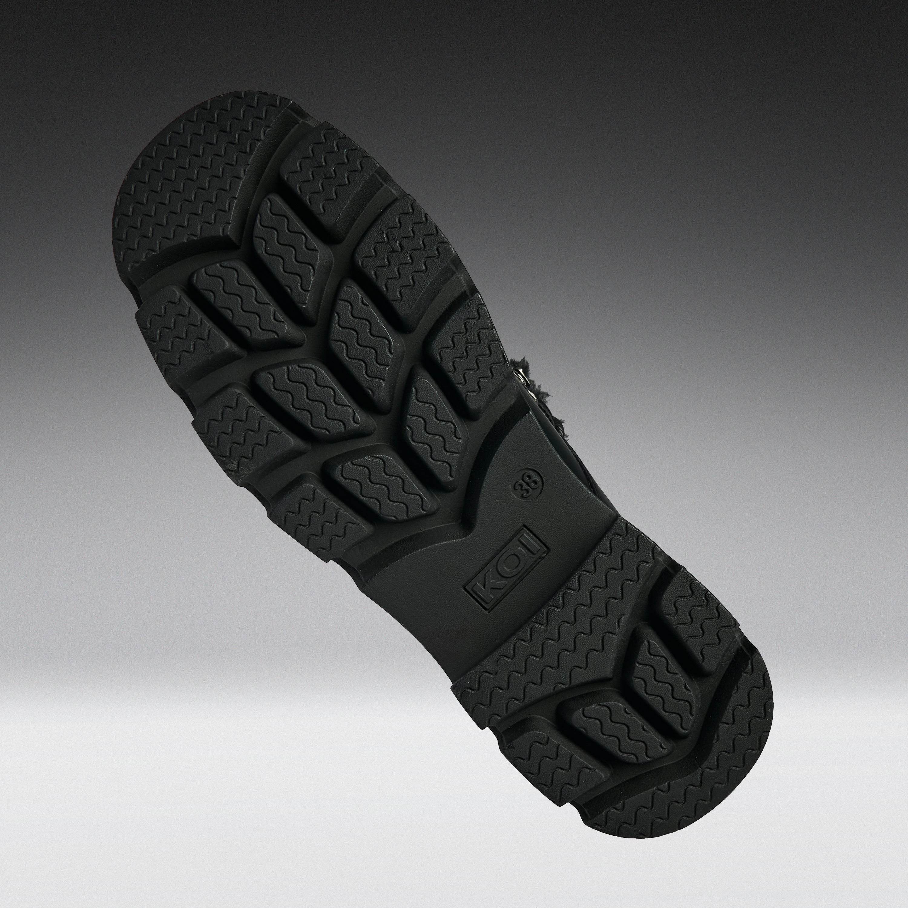 A close-up of a black textured shoe sole, showing the tread pattern and embossed K-Swiss logo, set against a dark gray gradient background.