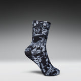 A single crew sock with a black and white comic book panel print, shown in a floating pose against a dark gray gradient background.