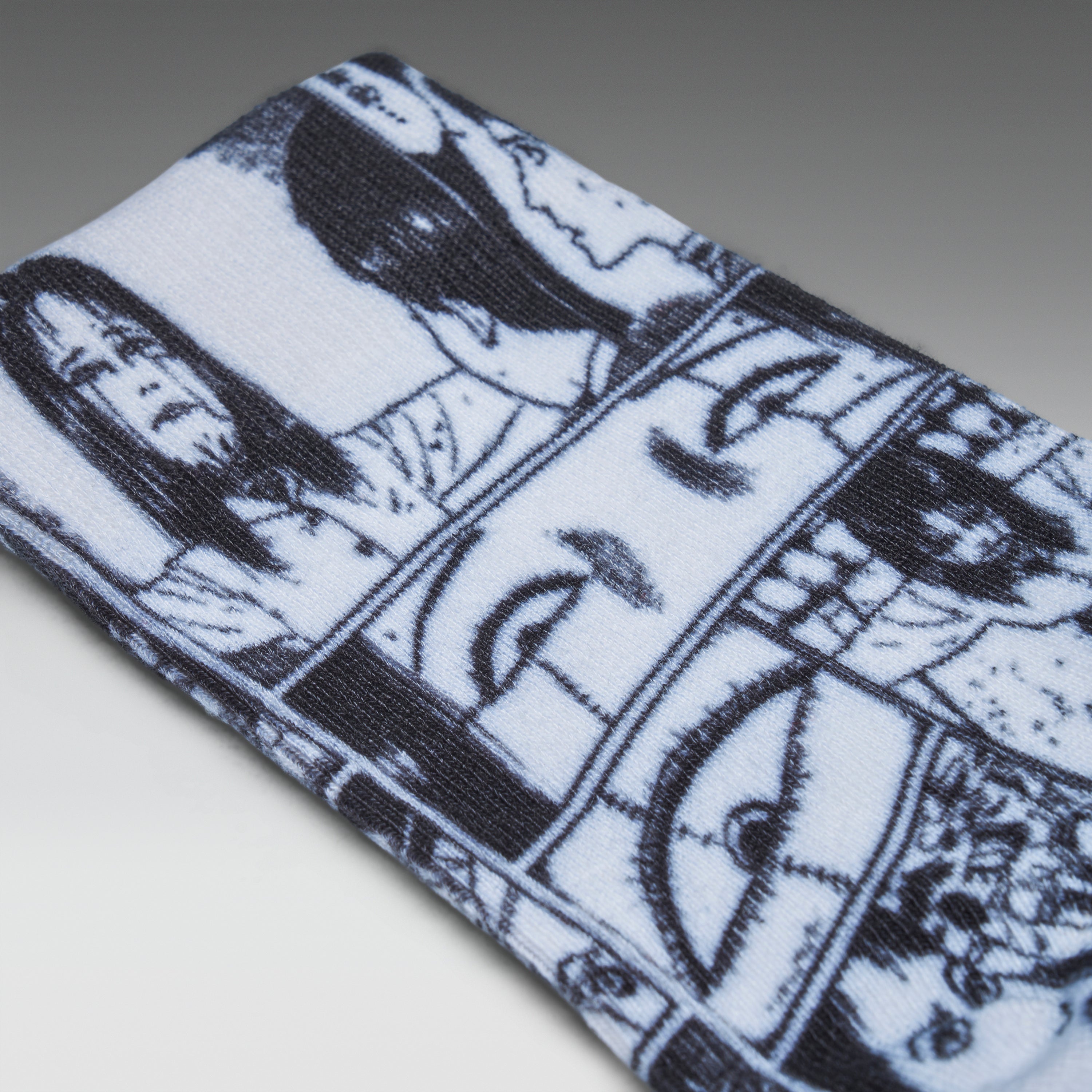 A close-up of a white knit fabric item, likely a sock or cuff, featuring a black and white comic-style illustration of faces and eyes.