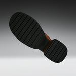 A close-up of a black rubber boot sole with deep grooves and a brown heel, shown against a dark-to-light gray gradient background.