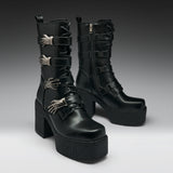 A pair of black leather gothic ankle boots with platform soles, chunky block heels, and silver metallic skeletal hand embellishments, shown against a dark gray studio background.