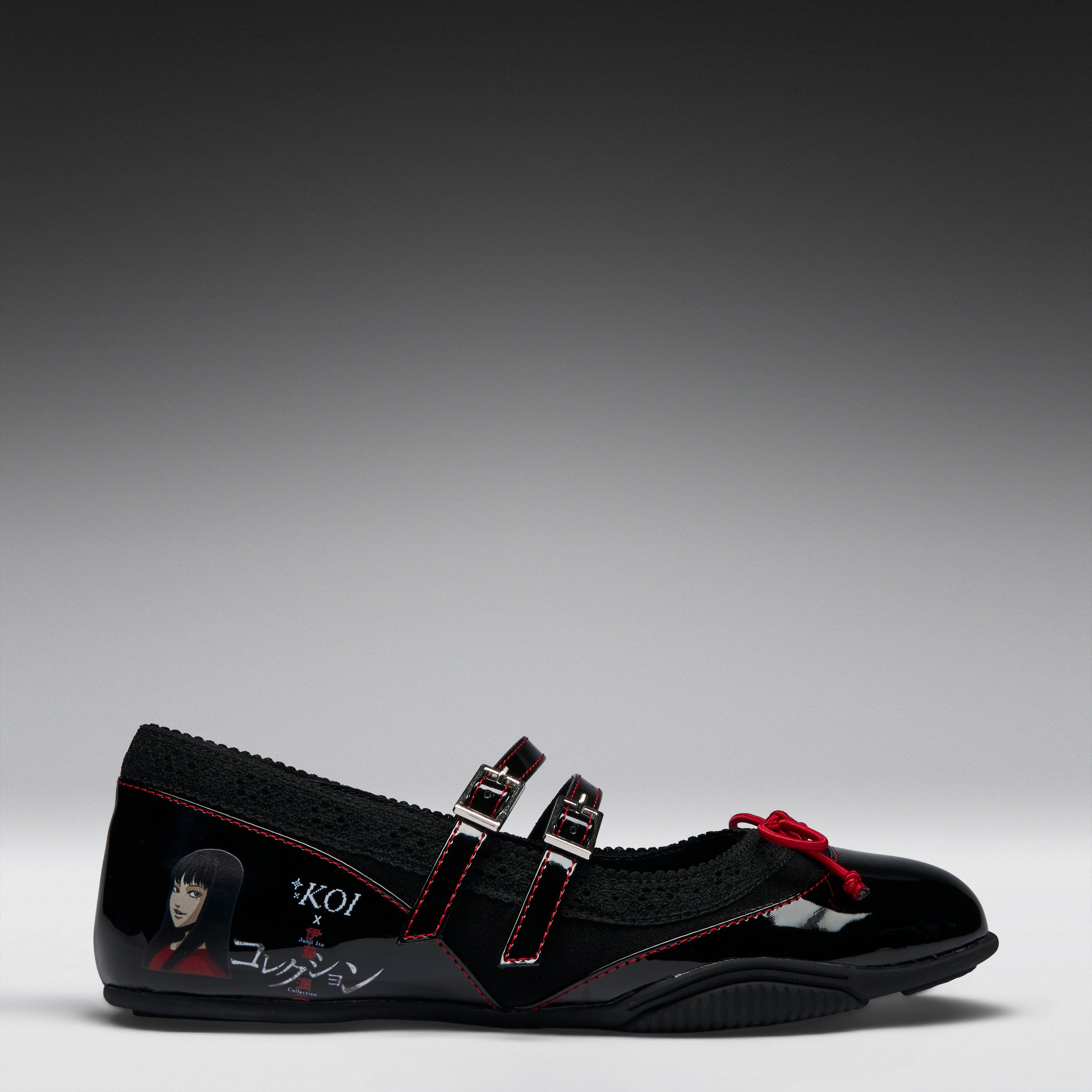 A black Mary Jane-style shoe with double straps, red contrast stitching, a red bow detail, and graphic character artwork on the side, photographed on a gray gradient studio background.