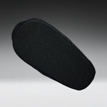 A black textured shoe cushion with a perforated grip pattern, shown floating against a dark gray gradient background.