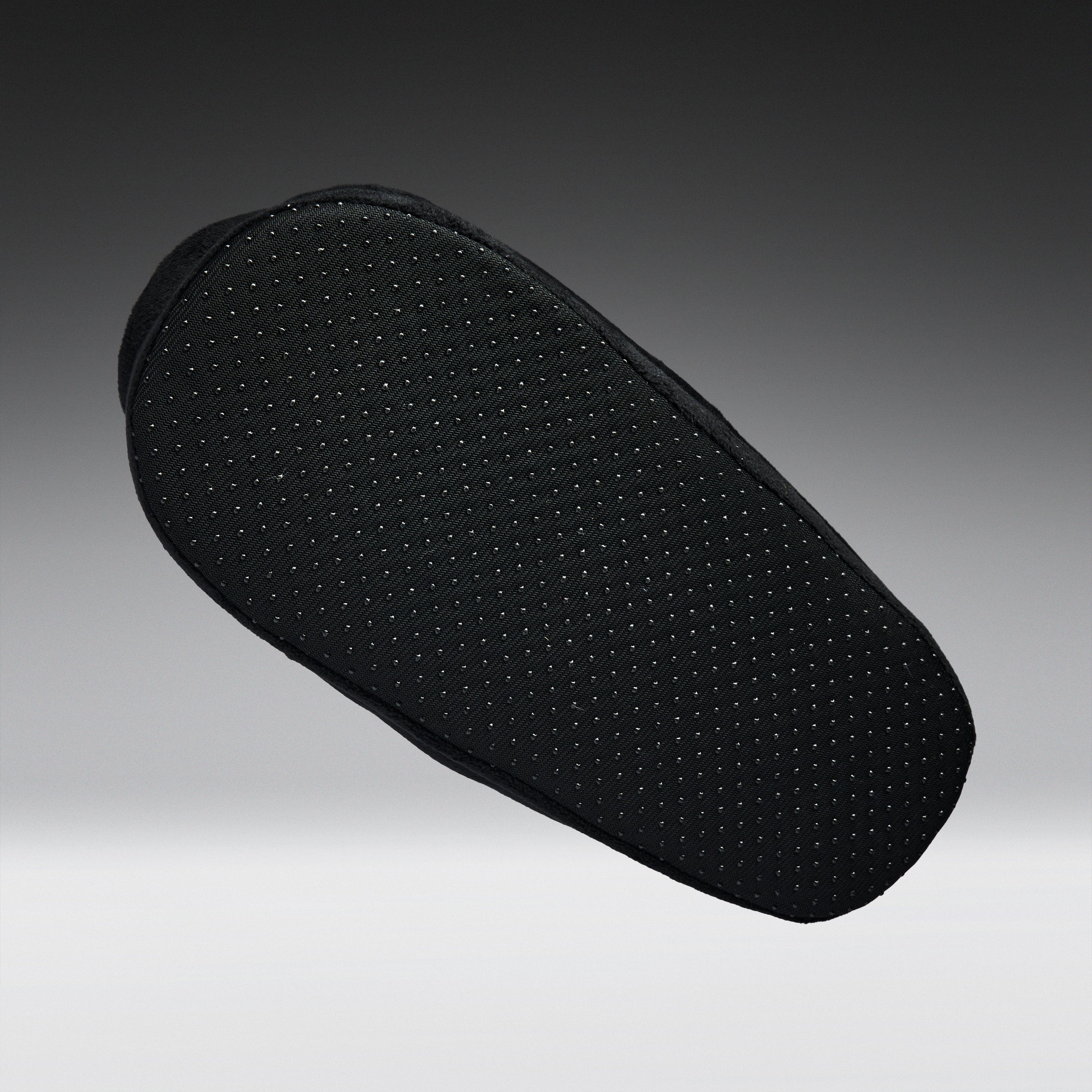 A black textured shoe cushion with a perforated grip pattern, shown floating against a dark gray gradient background.