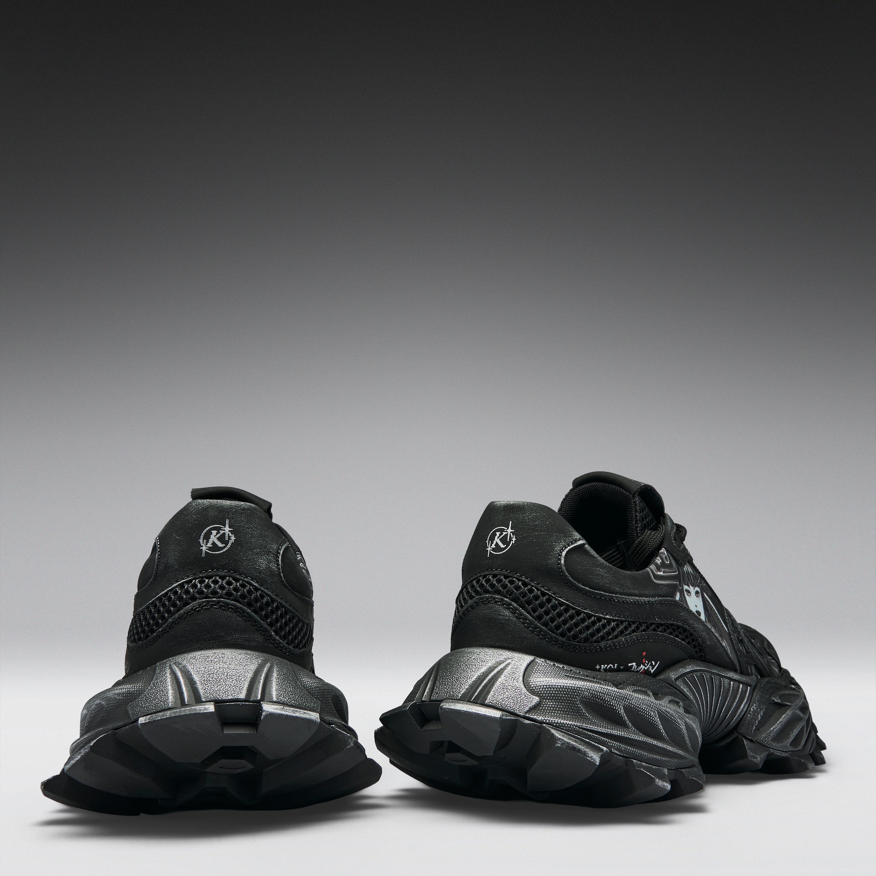 A pair of black chunky sneakers shown from the rear, featuring textured black soles and a circular logo on the heel, set against a dark gray gradient studio background.