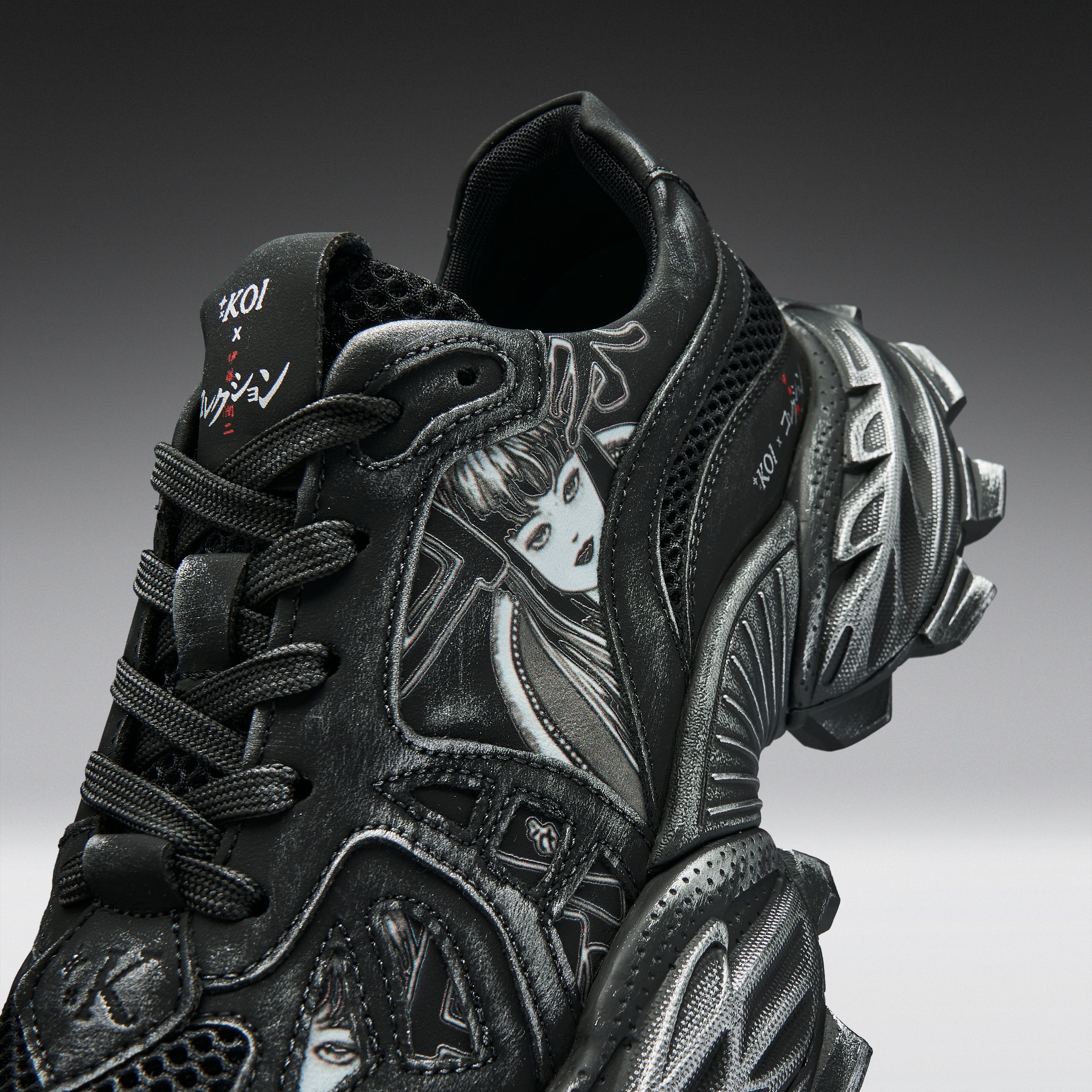 A close-up studio shot of a black chunky sneaker with sculptural layered soles, mesh side panels, and graphic face details in white and gray, photographed against a dark gray gradient background.