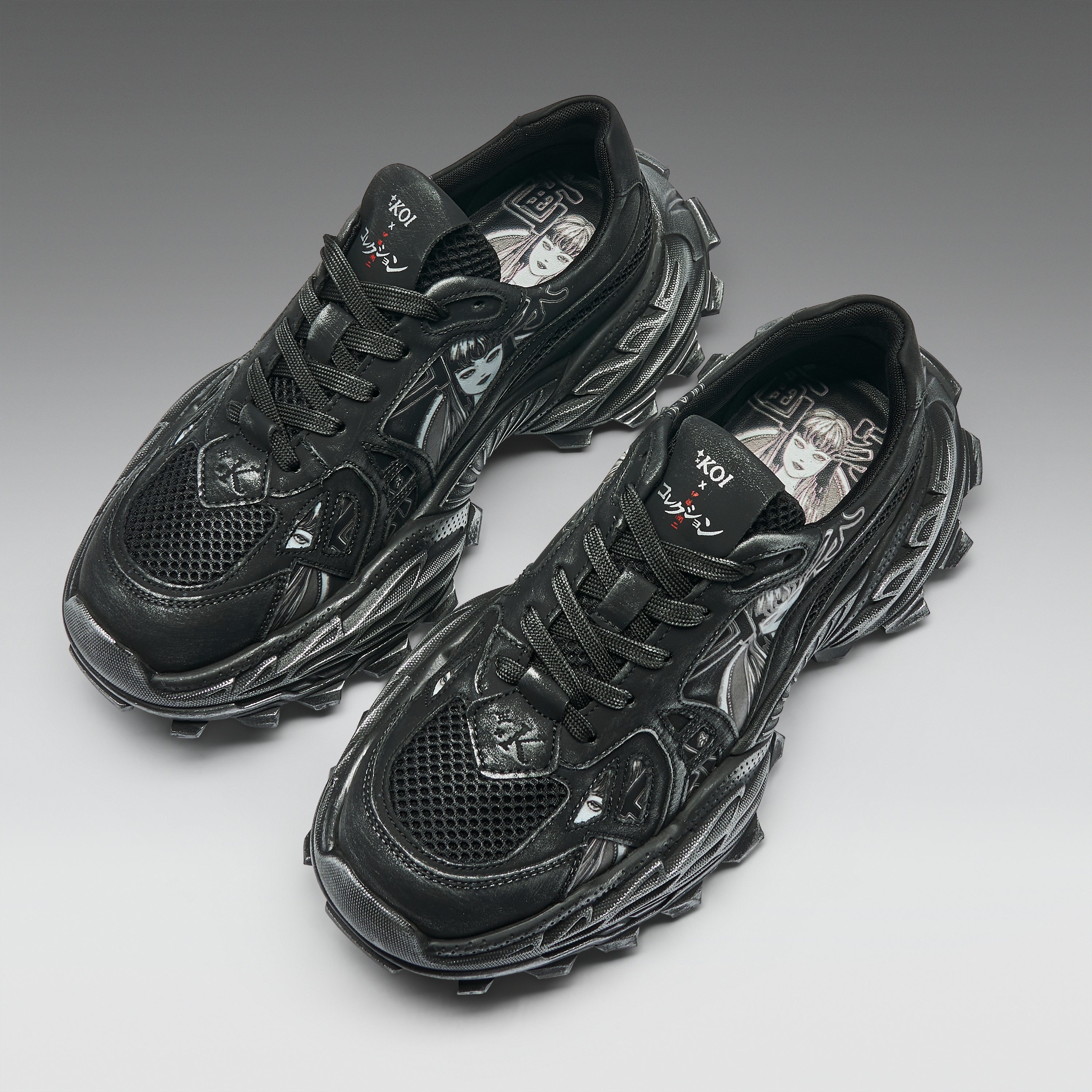 A pair of black chunky sneakers with textured, sculptural soles and mesh panels, photographed on a clean gray gradient background.