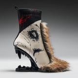A highly stylized, sculptural ankle boot with a black and beige animal-print body, a brown fur collar, and a black mechanical claw heel, displayed on a gray gradient studio background.