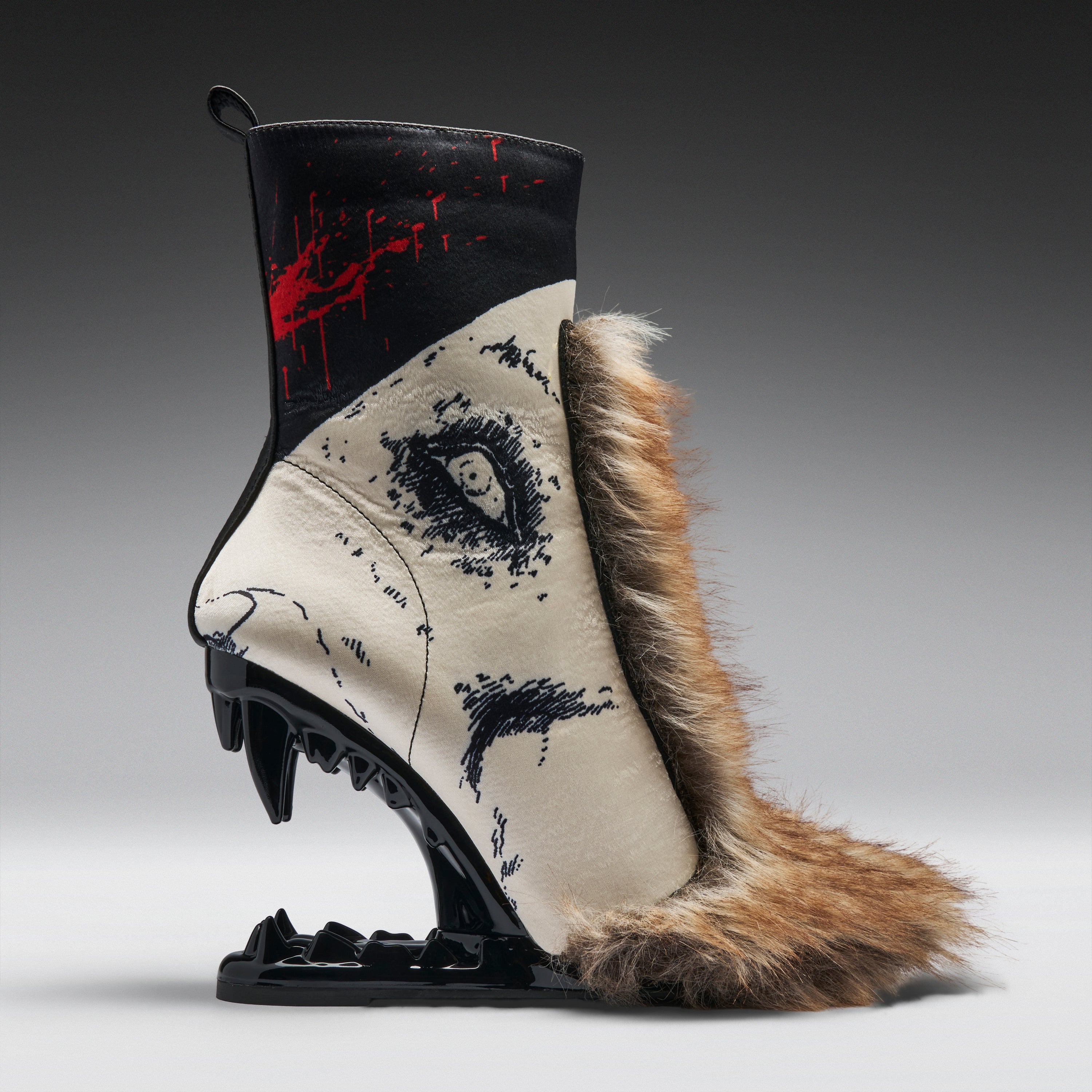 A highly stylized, sculptural ankle boot with a black and beige animal-print body, a brown fur collar, and a black mechanical claw heel, displayed on a gray gradient studio background.