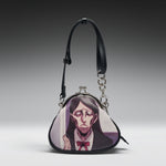 A small black purse with a printed anime-style portrait of a woman with long dark hair and a red bow. The purse has a black shoulder strap, silver-tone metal clasp, and chain detail, photographed on a gray gradient studio background.