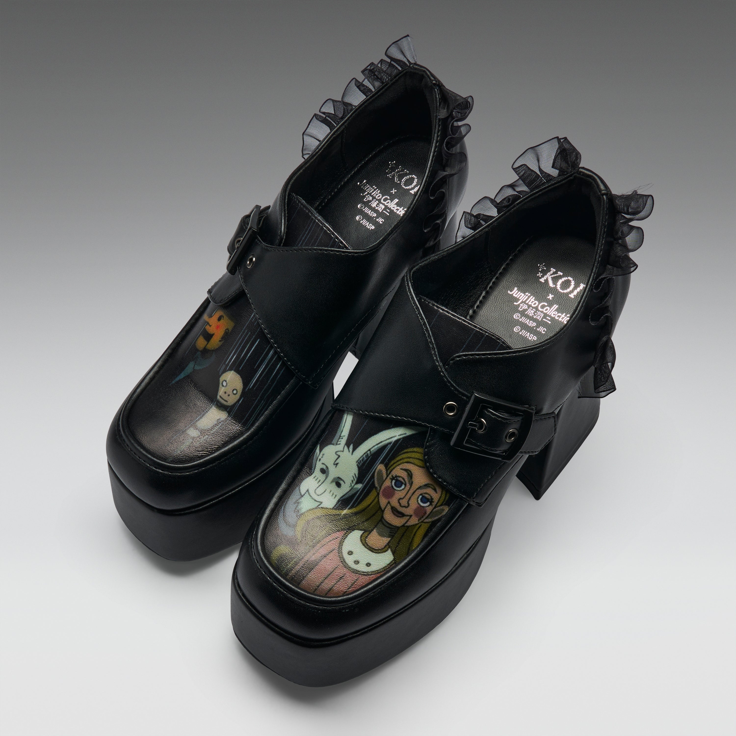 A pair of black platform Mary Jane-style shoes with ruffled trim and block heels, featuring printed character artwork on the toe boxes. The shoes are photographed on a clean light gray studio background.