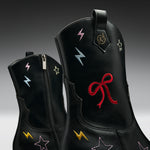 Black leather boots with embroidered lightning bolts and stars in multiple colors, featuring a red bow embroidery on the front boot.