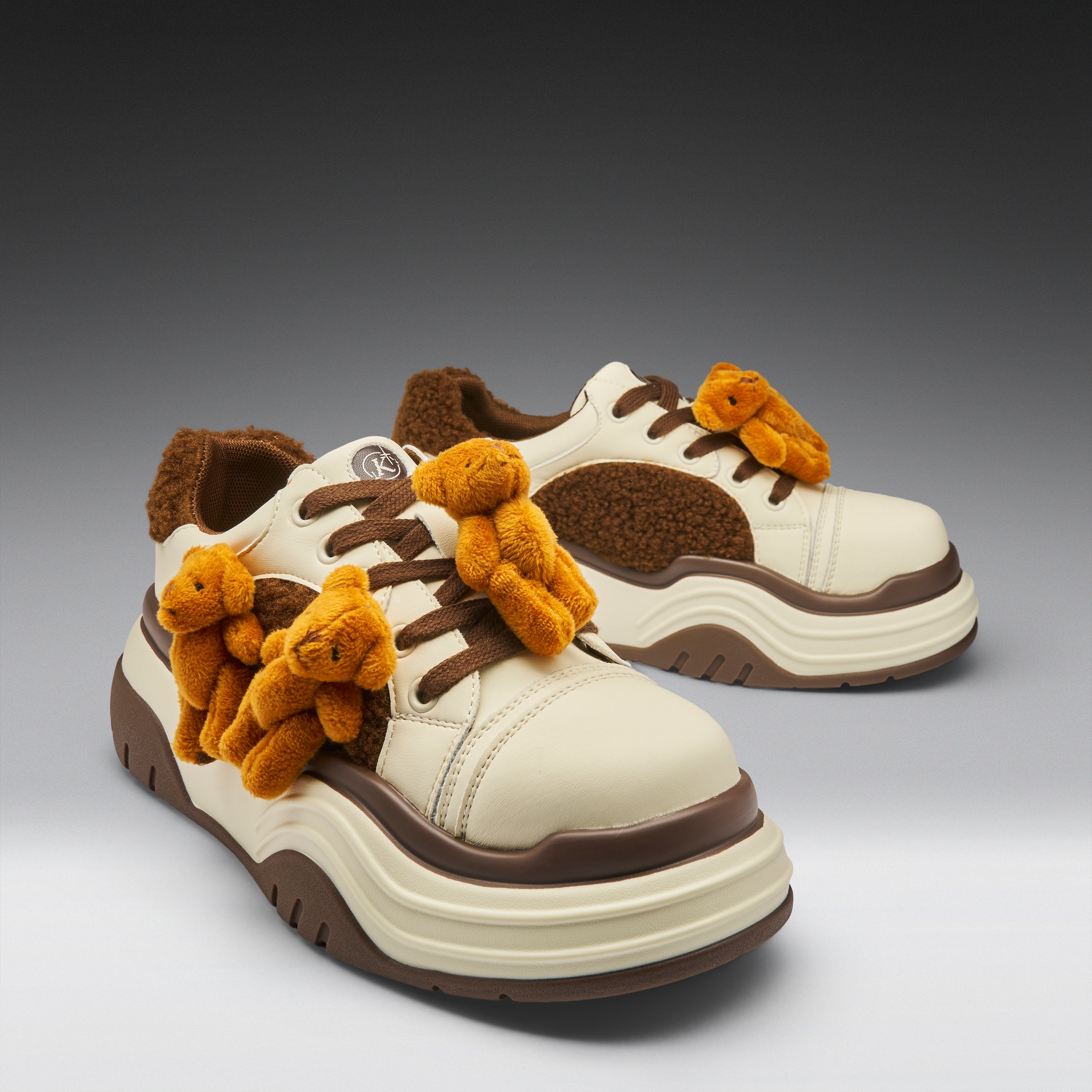 Pair of white sneakers with brown accents and teddy bear decorations on a gradient background