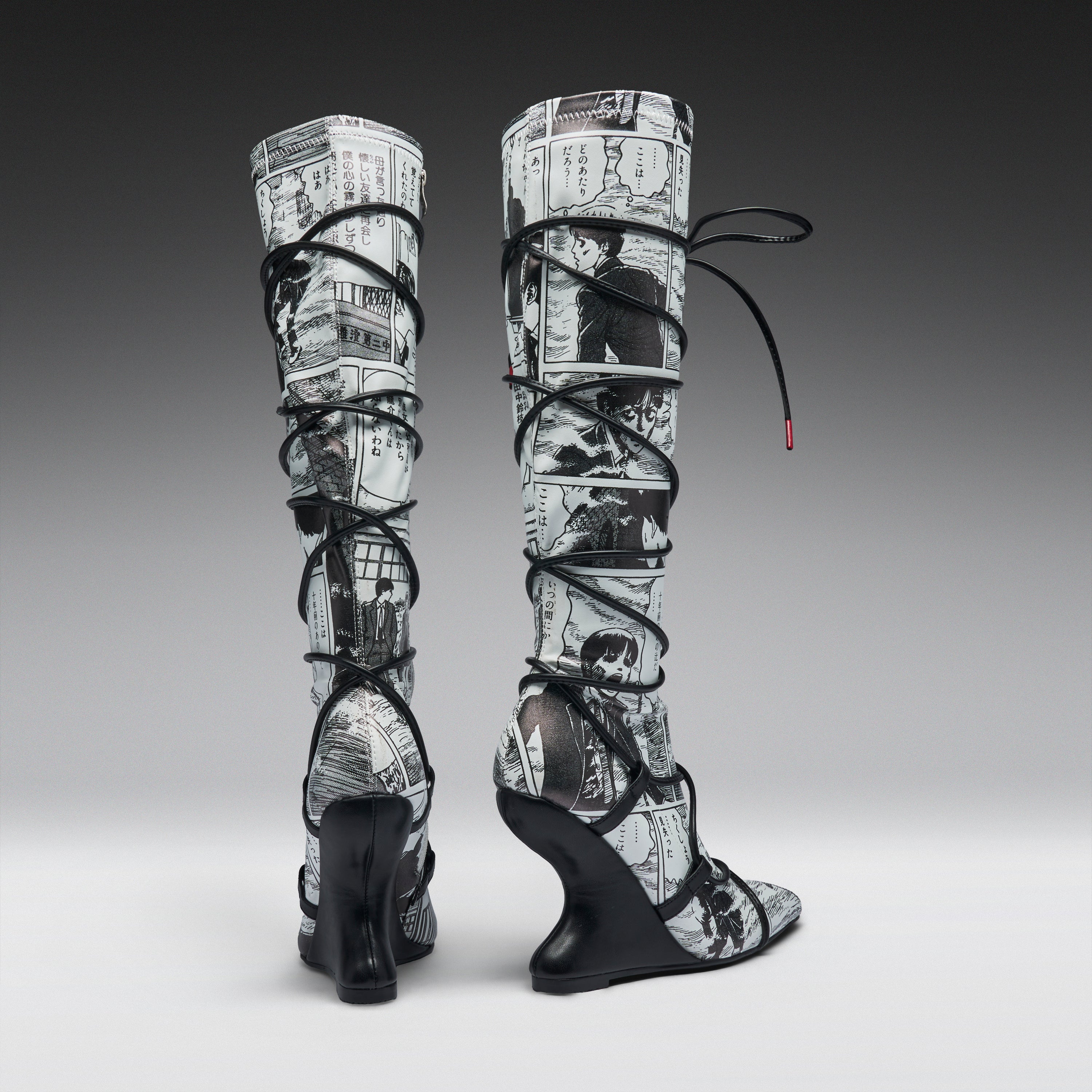 A pair of high-heeled, over-the-knee boots featuring a black and white newspaper print pattern wrapped around the shafts, with black lace-up straps and wedge heels, shown against a gray gradient studio background.