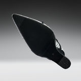 A black pointed-toe shoe shown from the sole side, featuring a textured black rubber outsole and a silver metallic side accent, set against a dark-to-light gray gradient background.
