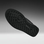 A black rubber shoe sole shown from a top-down angle against a dark gray to light gray gradient background.