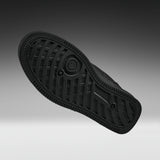 A black rubber shoe sole shown from a top-down angle against a dark gray to light gray gradient background.