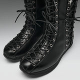 A pair of black leather lace-up boots with silver metal eyelets, shown on a neutral gray background.