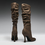 A pair of tall, slouchy knee-high boots in a dark brown suede-like material, shown from the back against a dark-to-light gray gradient studio background.