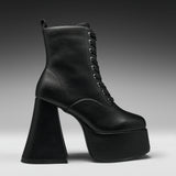 A single black leather lace-up ankle boot with a dramatic high block heel and platform sole, shown in profile against a dark gray gradient studio background.