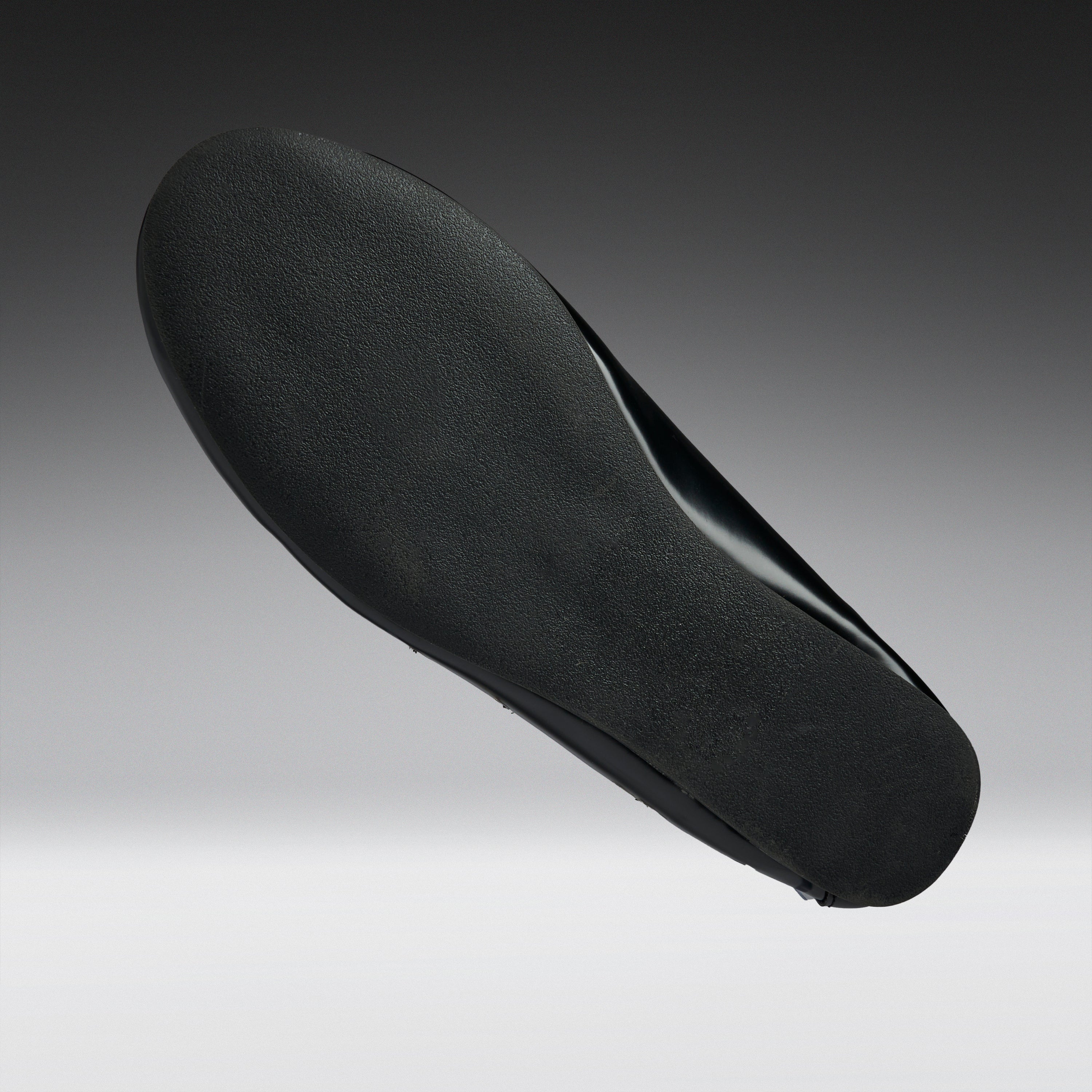 A black shoe insole shown floating against a gradient gray background.