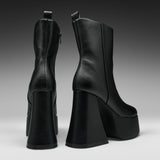 A pair of black leather ankle boots with chunky platform heels, shown from the back and side against a dark gray gradient studio background.