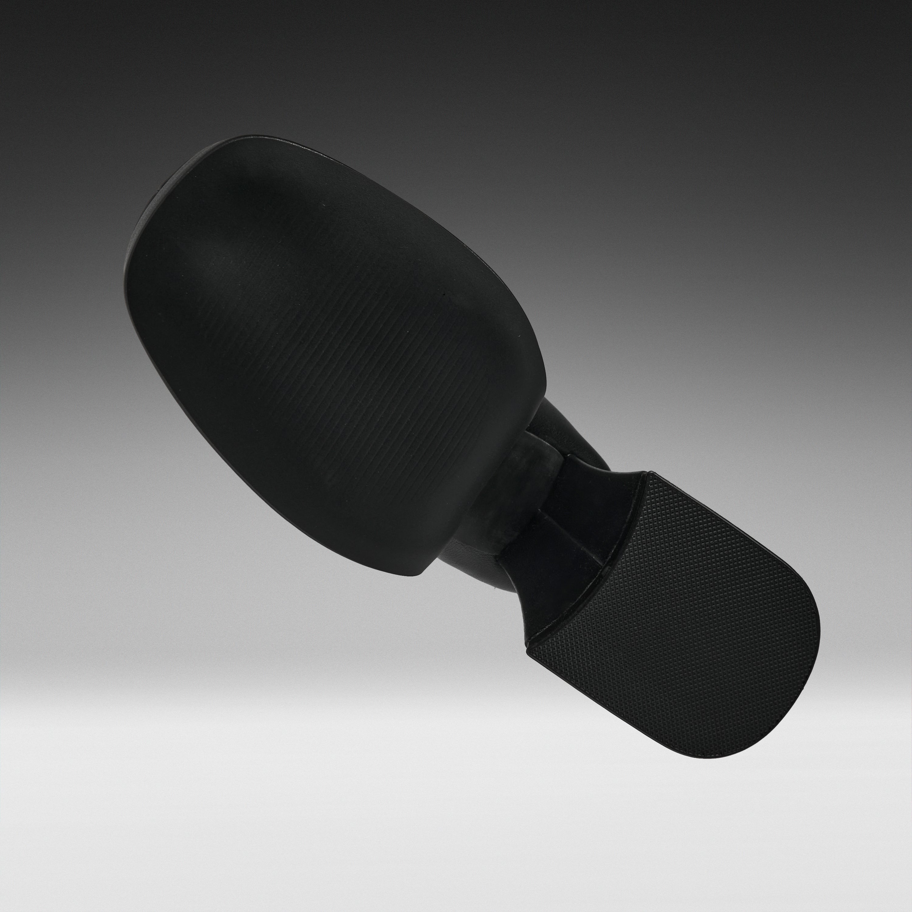 A black textured headrest or support cushion with a curved top section and a rectangular base, shown floating against a dark-to-light gray gradient background.