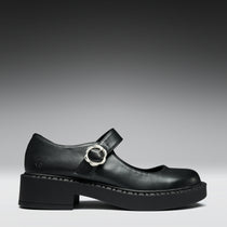 Black leather shoe with a round buckle on a gray background