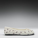 A single cream-colored ballet flat shoe with a repeating pattern of black and brown ants, shown in profile against a dark-to-light gray gradient studio background.