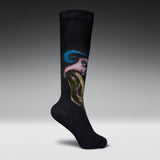 A single black crew sock with a surreal graphic print of a face with blue hair and a green snake, shown against a gray gradient studio background.