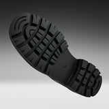 A close-up of a black rubber shoe sole with deep lugs and a textured tread pattern, shown against a dark-to-light gray gradient background.