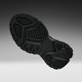 A close-up of a black athletic shoe's textured outsole, shown from a side angle against a dark-to-light gray gradient background.