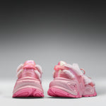 A pair of pink chunky sneakers shown from the back, featuring fuzzy white faux-fur trim and translucent pink soles, set against a dark-to-light gray gradient studio background.