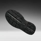 A black rubber shoe sole shown from a top-down angle against a dark gray to light gray gradient background.