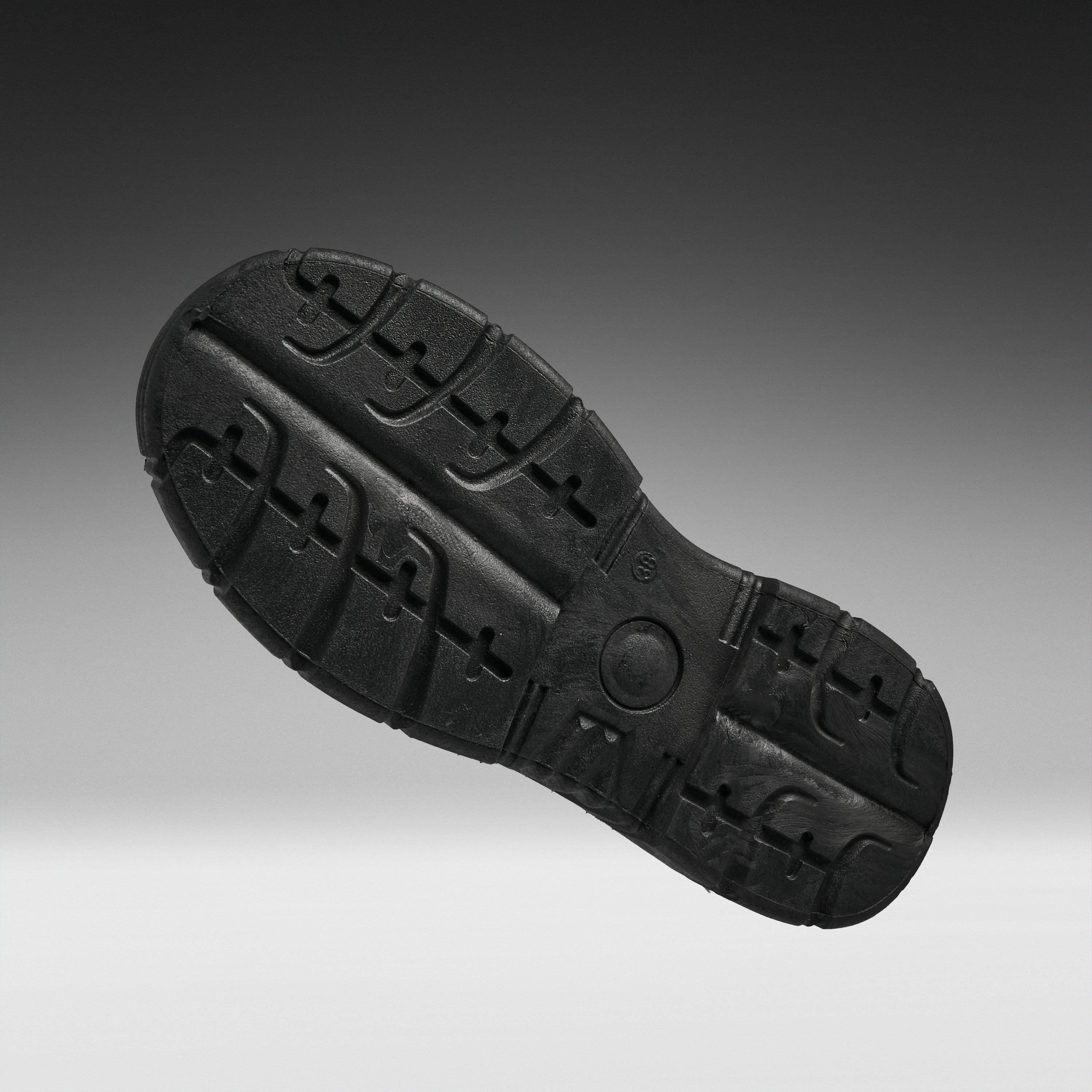 A black rubber shoe sole shown from a top-down angle against a dark gray to light gray gradient background.