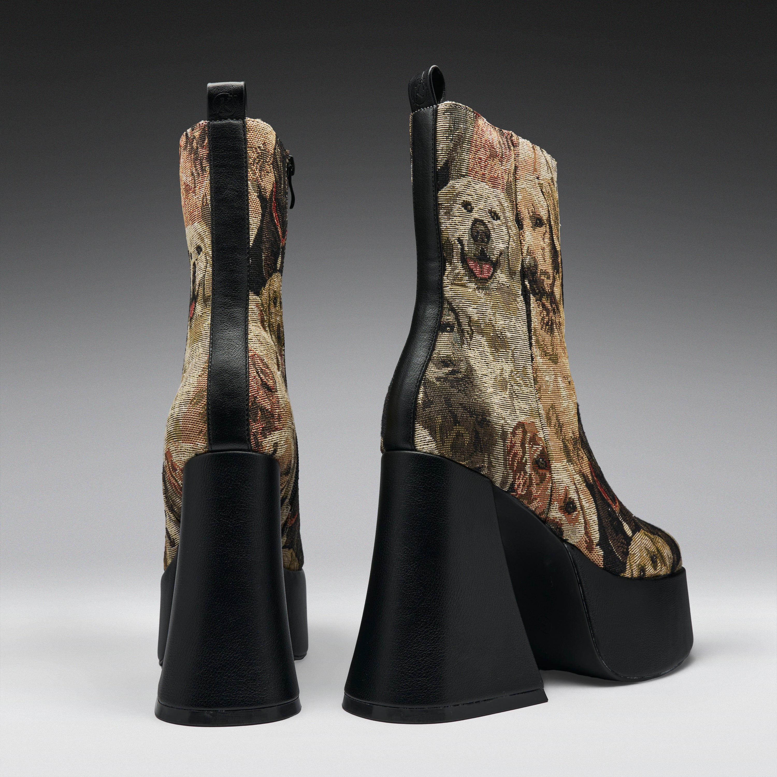 A pair of high-heeled platform ankle boots shown from the back, featuring a brown and beige dog-print fabric with black leather trim and chunky black platform heels.